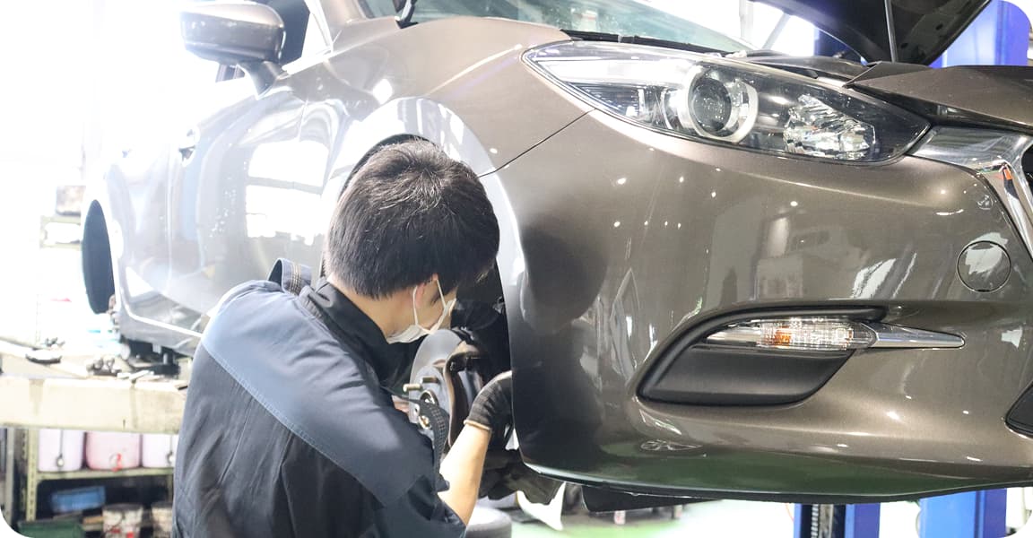 リフトアップされた車を整備する作業員