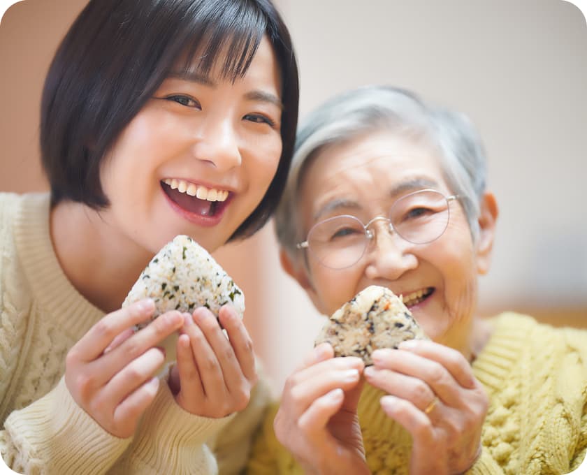 おにぎりを持って笑顔を見せる若い女性と高齢女性